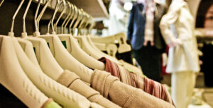 Kleider auf einem Kleiderhaken in einem Geschäft mit Schaufensterpuppen